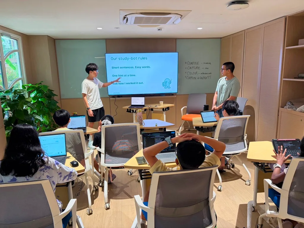 An instructor points to study-bot rules while children follow along at their tables